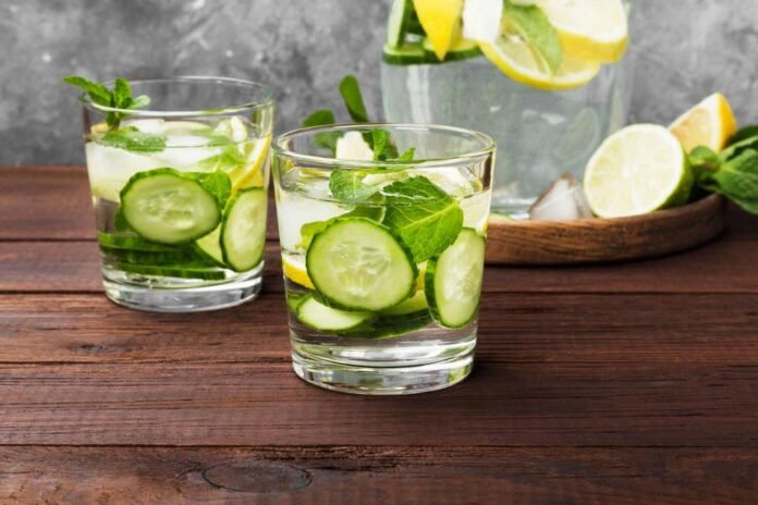 Detox drink with cucumber, lemon and mint in glasses on a wooden background