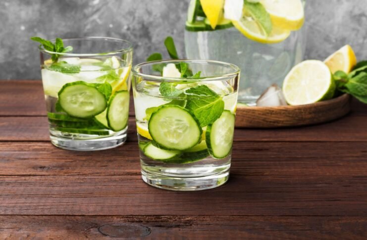 Detox drink with cucumber, lemon and mint in glasses on a wooden background